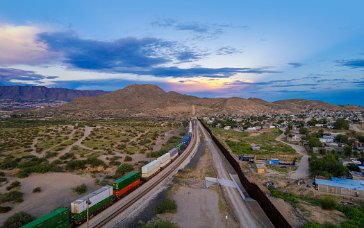 Train passing alongside Puerto de Anapra town at the border between USA and Mexico - drone view