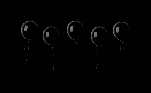 Black balloons floating in mid-air against black background with copy space.