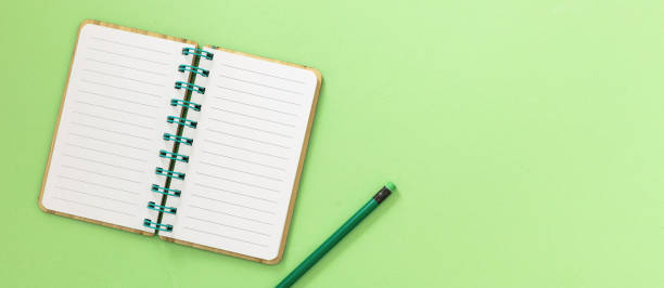 istock Blank open spiral notepad. Paper notebook and pencil with eraser on light green 1430233243