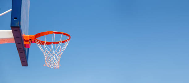 Basketball hoop, red ring and net on backboard, clear blue sky