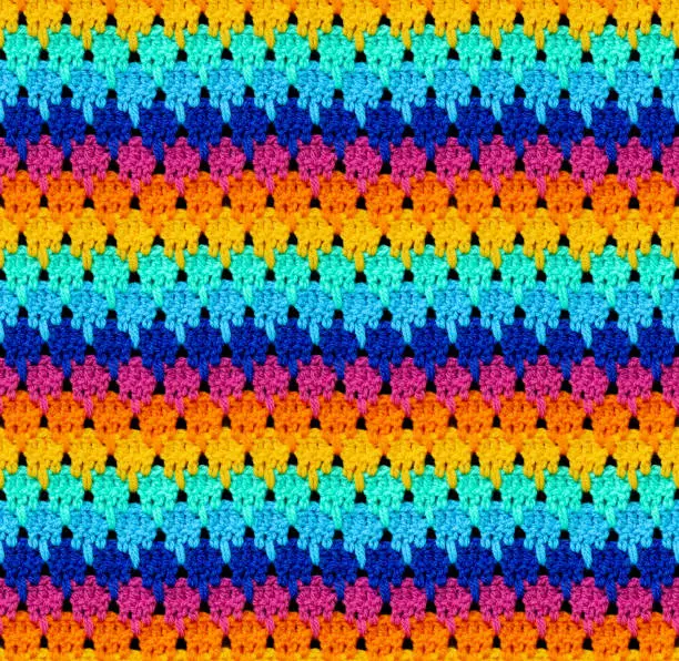 Seamless knitted texture. The pattern is crocheted from bright contrasting colors of acrylic yarn. Ethnic color motifs.