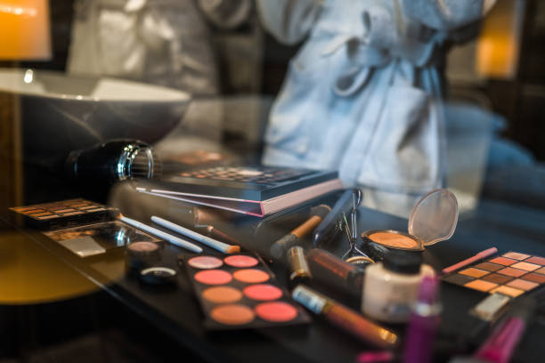 Women standing in front of the mirror and picking various cosmetic products for their makeup look.