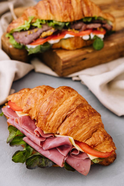 istock French croissant sandwich with lettuce , cheese , tomatoes and ham 1430252300