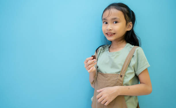 heureuse petite fille en chocolat sur fond de menthe. petite fille mangeant du chocolat posant sur fond bleu en studio, souriant à la caméra. concept de dent sucrée. - 5904 photos et images de collection