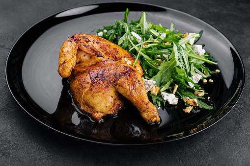 fried chicken with arugula salad on black plate