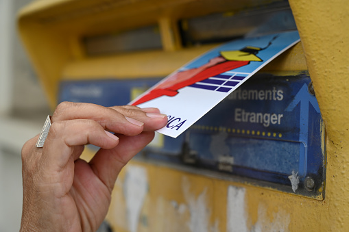 Ajaccio, France, september 29, 2022 : Hand putting a postcard in a mailbox in France