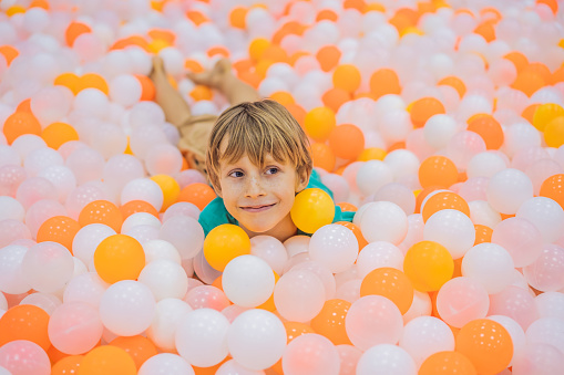 Child playing in ball pit. Colorful toys for kids. Kindergarten or preschool play room. Toddler kid at day care indoor playground. Balls pool for children. Birthday party for active preschooler.