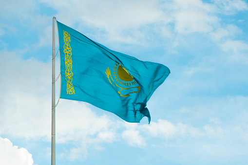 Flag of Kazakhstan on sky background. Waving flag of Republic of Kazakhstan. Fabric textures flowing flag of Kazakhstan.