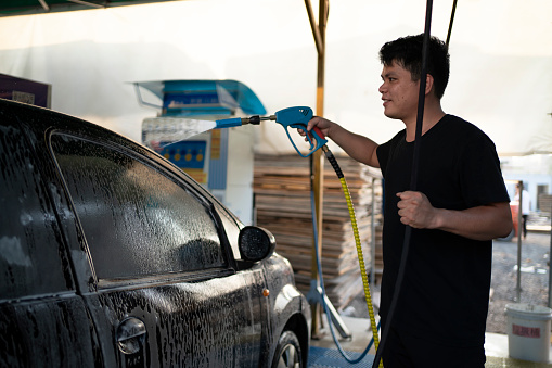 Man using high pressure equipment to wash car