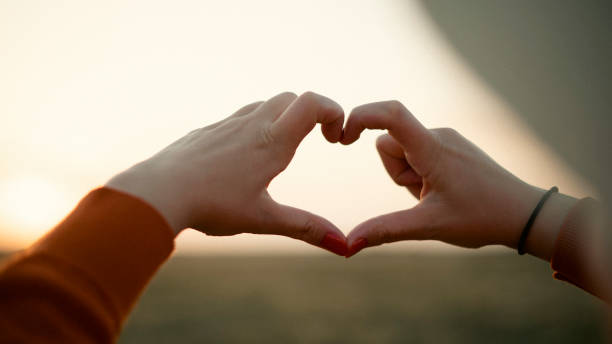 istock Making a heart shape with fingers against the sunset 1430278096