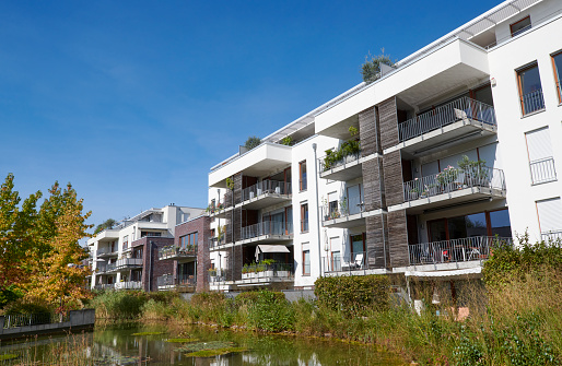 Contemporary white apartment houses, a pond in the foreground.