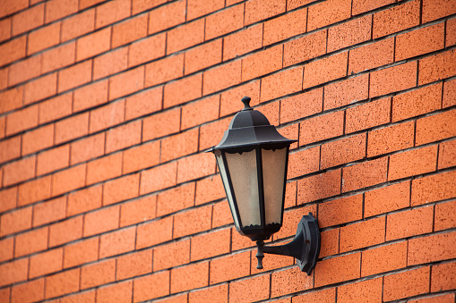 close up view of single classic black lamp or lantern on white wall with copy space.