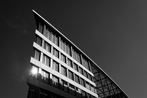 Black and white photograph of a part of a new office building with sun reflection, Germany