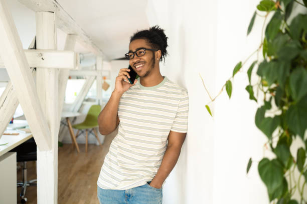 Portrait of a young African American relaxing at home and telephoning stock photo