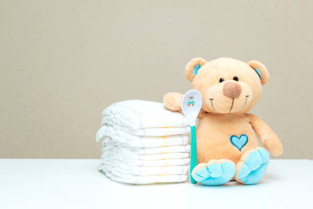 istock Stack of diapers with toy teddy bear with spoon on table. set for baby shower with copy space 1430282801