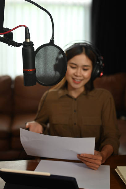 istock Charming asian female podcaster using a microphone and laptop recording audio for channel in her home studio. 1430284480