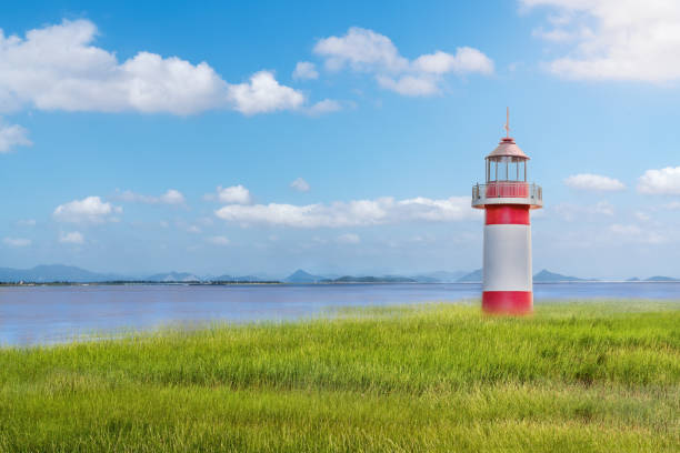 Red lighthouse by the sea under blue sky and white clouds