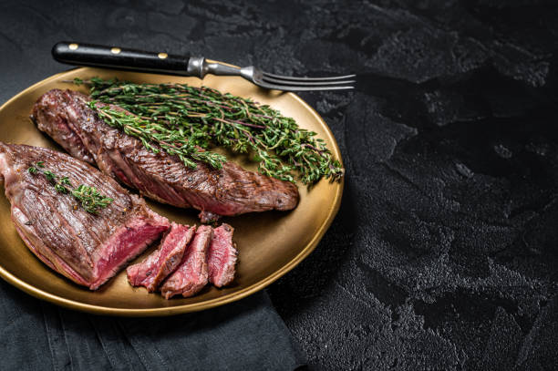 istock BBQ grilled Bavette Bavet beef meat steak with herbs on a plate. Black background. Top view. Copy space 1430292099
