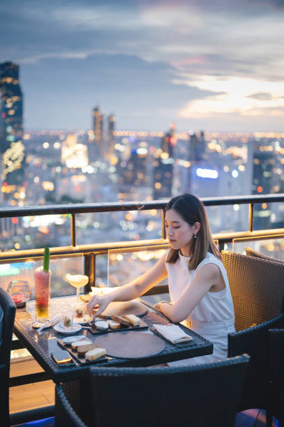 amigos se encontrando e bebendo coquetel juntos no restaurante da cobertura do arranha-céu na metrópole ao pôr do sol de verão. - hotel restaurant women luxury - fotografias e filmes do acervo