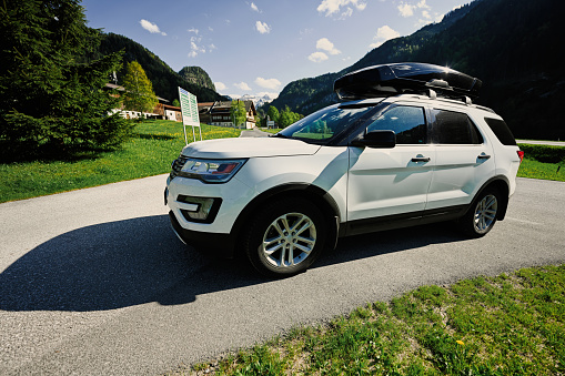 White SUV Car with the roof rack cargo box on road in Untertauern, Austria.