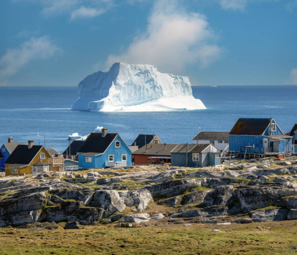 enormes icebergs que revestem as margens da charmosa cidade de qeqertarsuaq (antiga godhavn) na costa sul da ilha disko, na groenlândia ocidental. - greenland - fotografias e filmes do acervo