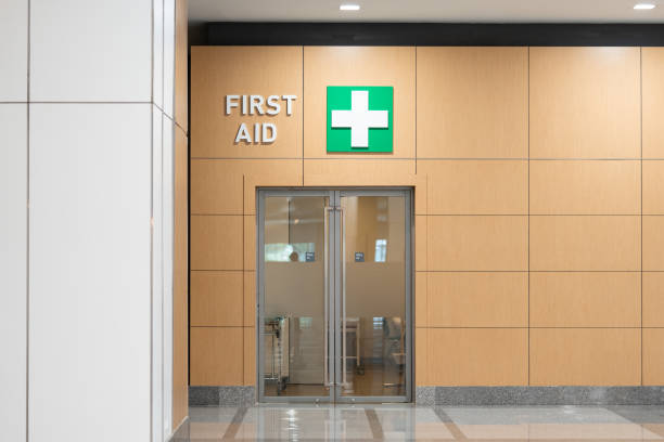 stanza di pronto soccorso all'interno di un edificio. decorato con dolore muro marrone chiaro, spingere e tirare la porta a un ingresso e porta aperta a sinistra per una passeggiata spaventosa su uno sfondo con luce fioca. - segnale di uscita demergenza foto e immagini stock