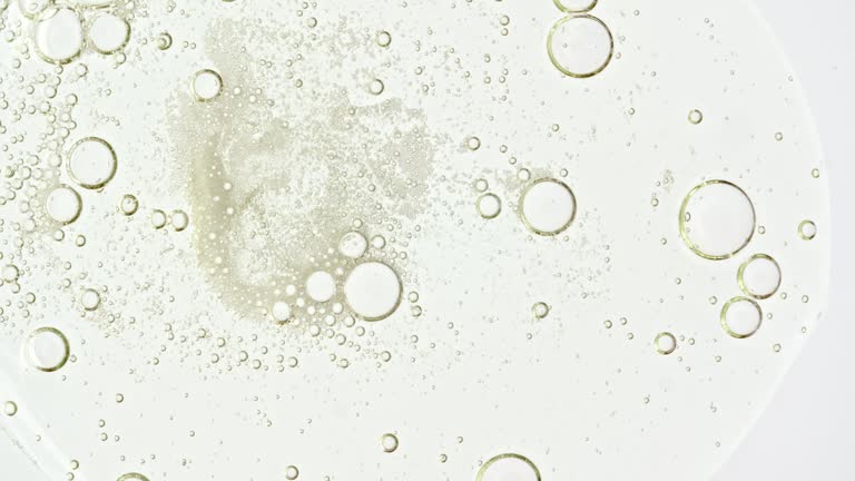 Transparent cosmetic gel fluid with molecule bubbles oil distribution on a white background. Macro Shot of Natural Organic Cosmetics, Medicine. Production Close-up. Slow Motion