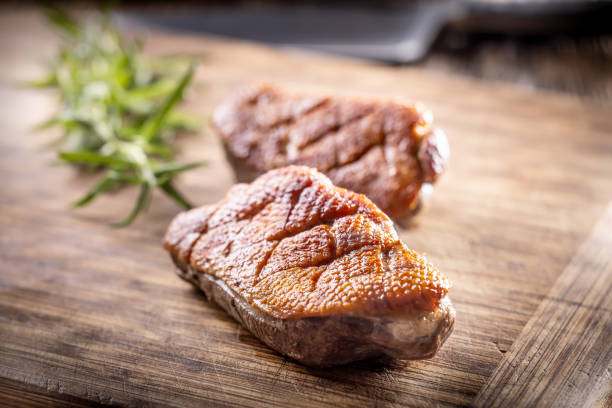 Roasted duck breast on a cutting board ready for slicing and serving.