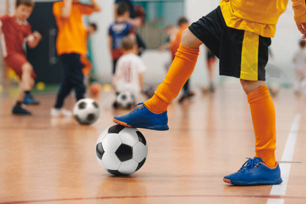 allenamento di calcio futsal per bambini. esercitazione di allenamento di calcio. giovane giocatore di calcio indoor con un pallone da calcio in un palazzetto dello sport. giocatore in divisa gialla. background sportivo - futsal indoors soccer ball soccer foto e immagini stock