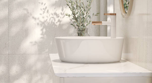 diseño moderno y minimalista de tocador de baño de color crema con encimera de mármol y lavabo de cerámica redonda blanca con jarrón de plantas de interior a la luz del sol desde la ventana - bathroom contemporary sink faucet fotografías e imágenes de stock