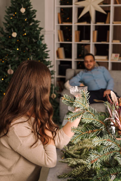 istock Young woman with glass is sitting at table. Man is looking in blurry focus. Selective focus. Images for articles about Christmas, holidays, relationships, family. 1430303320