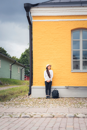 Woman (asian-caucasian) with hat and backpack, admiring meadows and sights of this historic area