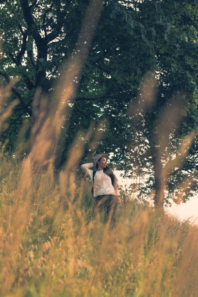 Woman (asian-caucasian) with hat and backpack, admiring meadows and sights of this historic area