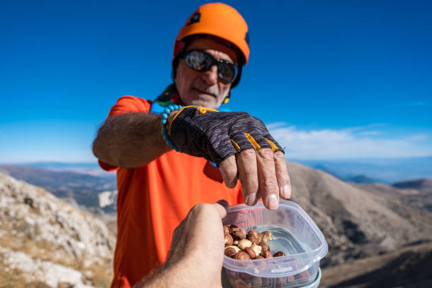 istock Mountain-climbing backpacker handing nuts in plastic bowl to old man 1430311569