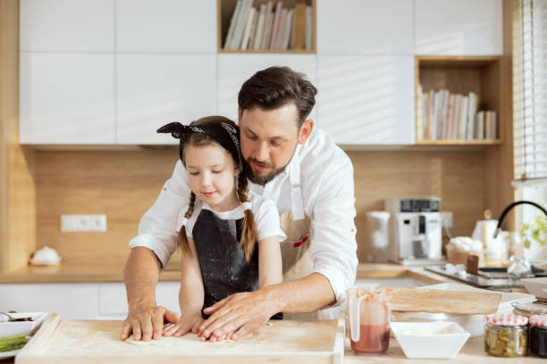 istock Curious daughter child kid cooking with father kneading rolling dough with hands for baking cooking homemade pizza in modern kitchen at home 1430313681