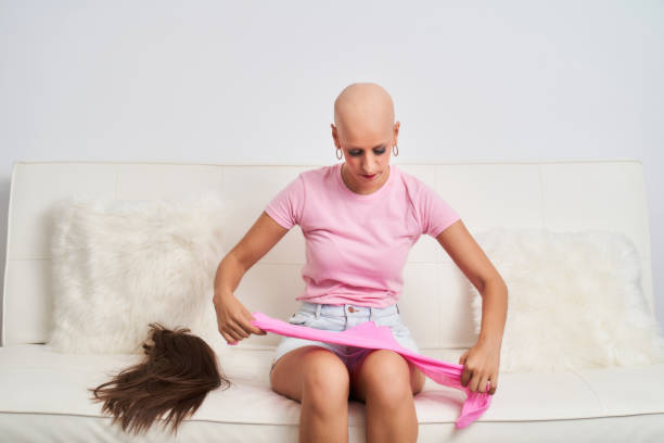 a woman with cancer has taken off her wig and is wearing a pink scarf stock photo