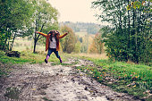 Teenage girl jumping over autumn puddles