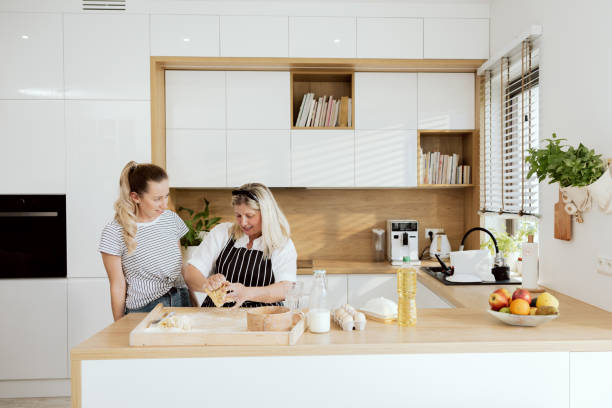 istock Kneading process. Happy elderly mother teaching daughter telling cookies pasta pizza recipe. Hoemade cookies pasta pizza baking preparing surprise for family dinner 1430315539