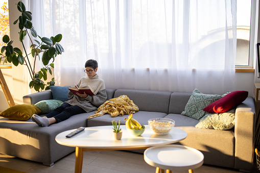 A young woman reading a book in an apartment's living room