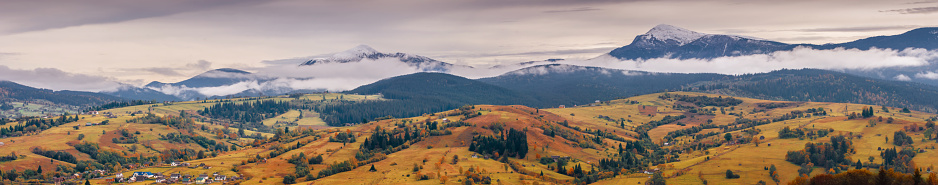 Panorama of Carpathian autumn valley under the snow-capped mountain ridge. Ukraine, Europe