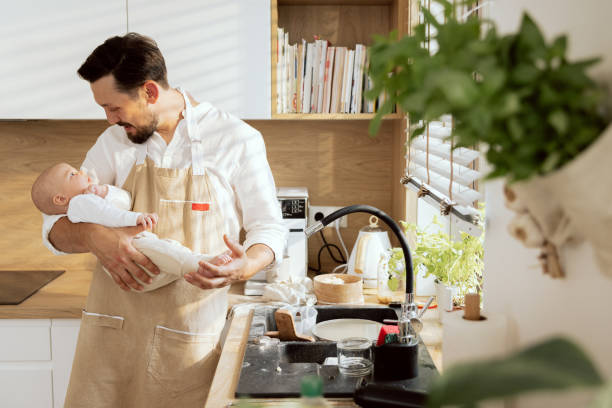 istock Well-looked husband spends time with kid holding in arm while applying tomato sauce on homemade prepared kneaded dough for baking pizza 1430319121