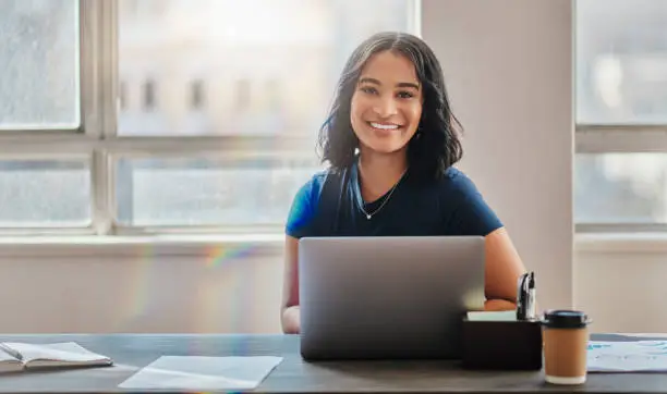 Photo of Business woman, smile and working on laptop in office or company looking happy and satisfied. Portrait of Brazilian female worker or employee typing email on computer and planning strategy for vision