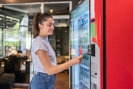 Woman  Selects Drink At Vending Machine And Pays With Credit Card