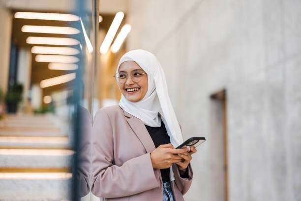 young muslim woman using smartphone indoors - hijab imagens e fotografias de stock