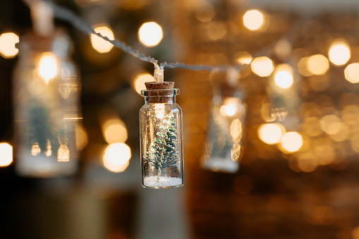 Glass bottles with snow and a Christmas tree on the background of beautiful bokeh. New Year's greeting card.A banner or a flyer for Christmas.
