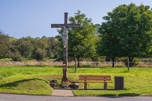 View towards a crucifix and a bench on a sunny autumn day