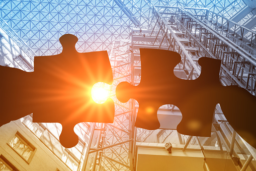 Cropped Hand Holding Jigsaw Pieces. hands trying to connect couple puzzle piece with sunset background. business partners combining puzzle pieces. association and connection. business strategy.