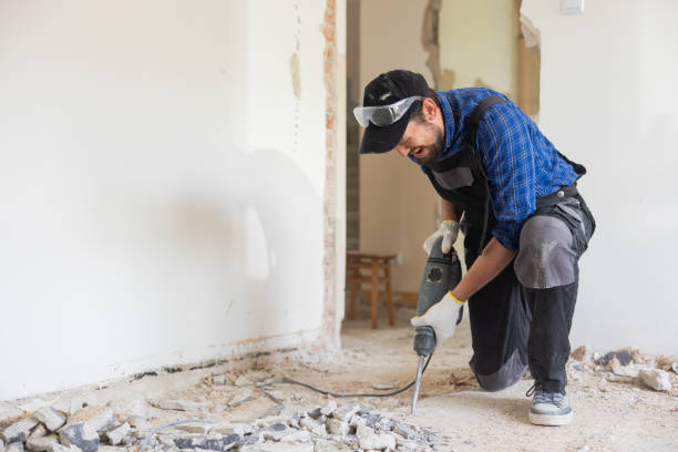 istock Removing a concrete floor with a hand hammer. Concrete rubble on the construction site of a house. Destruction of old tiles. Male construction worker fiercely working in overalls and protective mask 1430334585