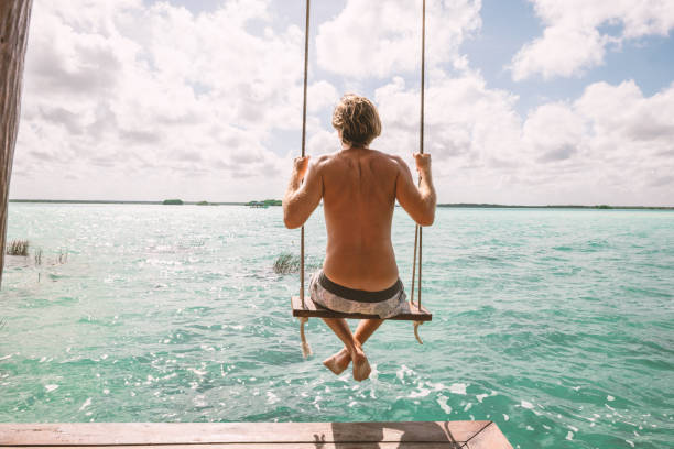 istock Young man having fun on swing in a beautiful lagoon on a sunny day 1430336671
