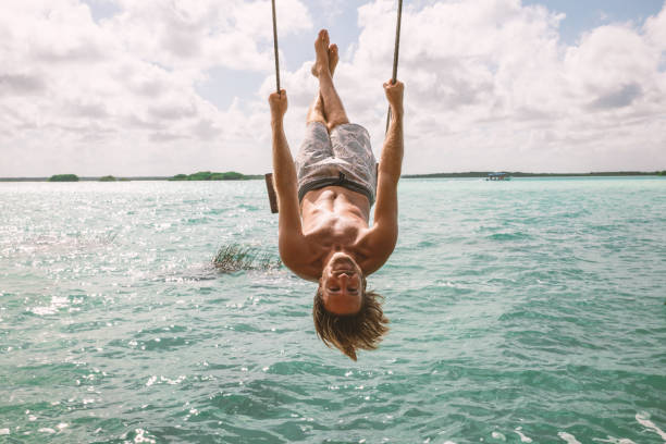 istock Young man having fun on swing in a beautiful lagoon on a sunny day 1430336796